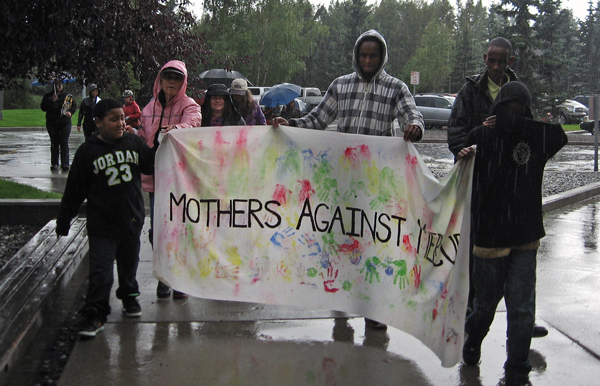 Demonstrators approach the Alaska Mental Health Trust Authority offices in pouring rain in Wednesday.  The group was there to protest coal development on lands owned by the Trust. Photo by Ellen Lockyer, KSKA - Anchorage.