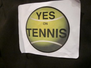 Supporters of building the Northern Lights Recreation Center which would house six indoor tennis courts wore stickers with the words 'Yes on Tennis' scrawled across a green tennis ball at the regular meeting of the Anchorage Assembly Tuesday night.