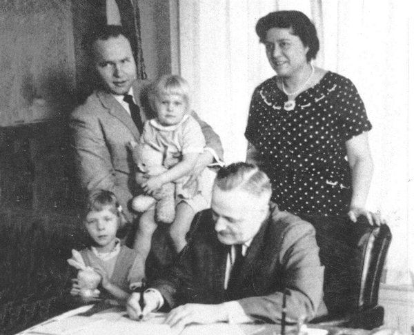 Joyce Kerttula stands behind Gov. Bill Egan as he signs a bill by Rep. Jay Kerttula, holding his daughter Anna. Beth Kerttula is standing beside the governor. (Uncredited photo via Alaska House Democrats)