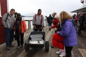 An employee in uniform answers tourists questions about a real halibut carted around the boardwalk. (Photo by Elizabeth Jenkins/KTOO)