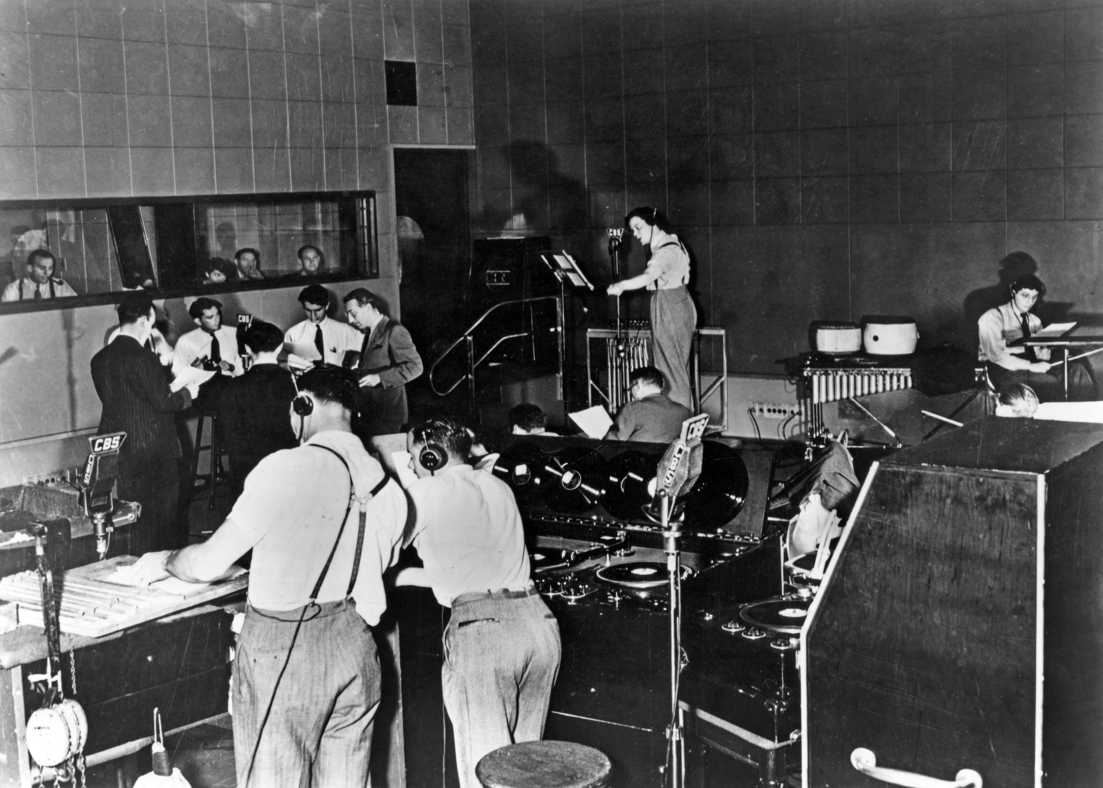 Orson Welles, 1938 Shown in rehearsal, standing, center background: director Orson Welles; seated, right: composer Bernard Herrmann NB: directing his Mercury Theatre of the Air troupe, such as created panic on the CBS radio broadcast of The War of the Worlds, October 30, 1938 (Photo Courtesy of Photofest, Inc.)