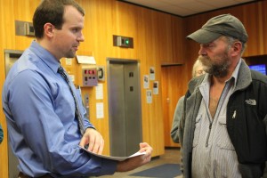 In the lobby of the Dimond Courthourse on Monday morning, attorney Nick Polasky hands trapper John Forrest court documents before the trial. Polasky is Kathleen Turley’s lawyer. (Photo by Lisa Phu/KTOO)