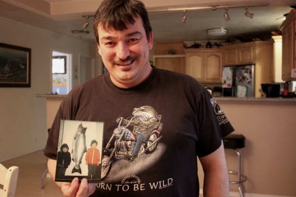 Rob Kenney holds a childhood picture of him and his brother next to a king salmon. (Photo by Lisa Phu/KTOO)