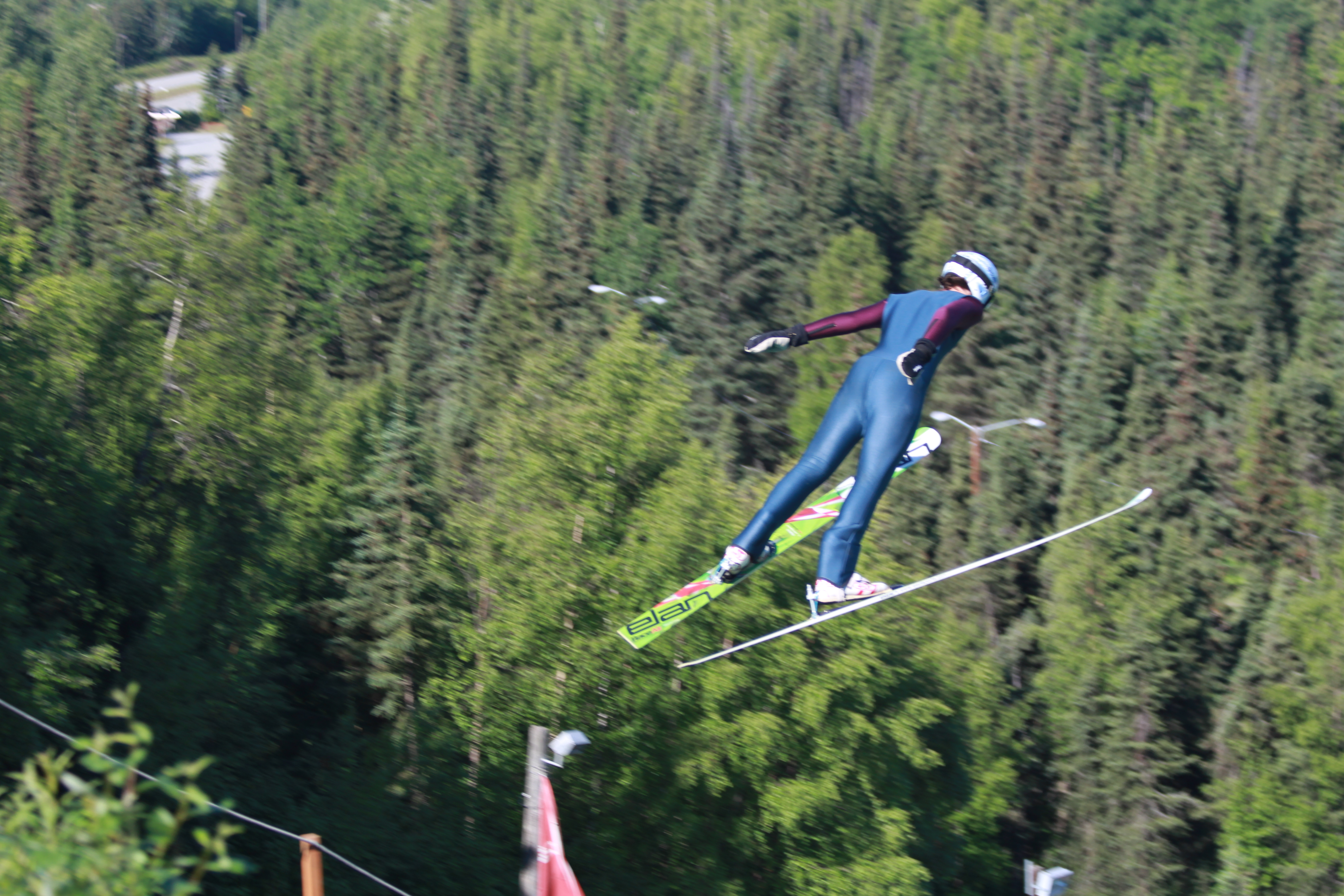 One of the young members of the Nordic Ski Association of Anchorage flies off of one of the new summer ski jumps. The Hilltop ski jump facility is the first of its kind to allow for ski jumping in the summer in Alaska. (Photo by Wesley Early, Alaska Public Media - Anchorage)