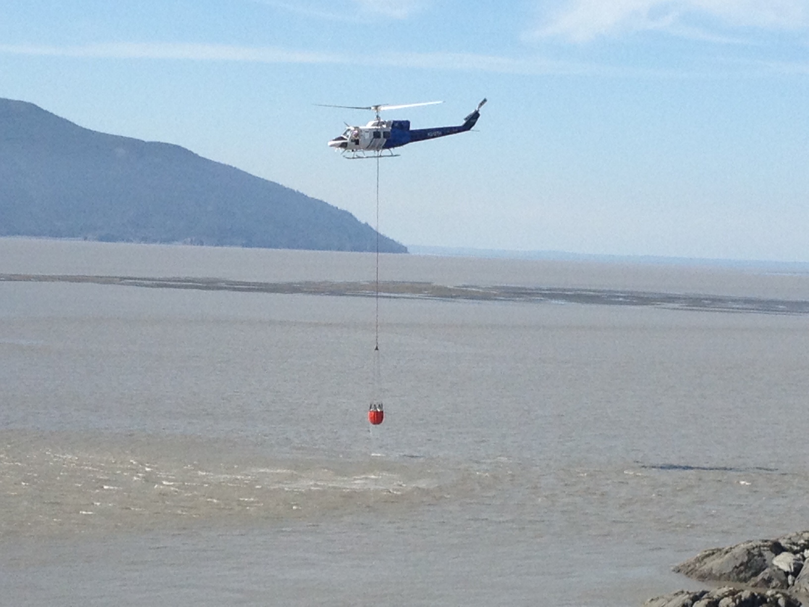 Forestry helicopter dips bucket into Turnagain arm while fighting the McHugh Creek wildfire on Sunday. (Photo by Ellen Lockyer, Alaska Public Media - Anchorage)