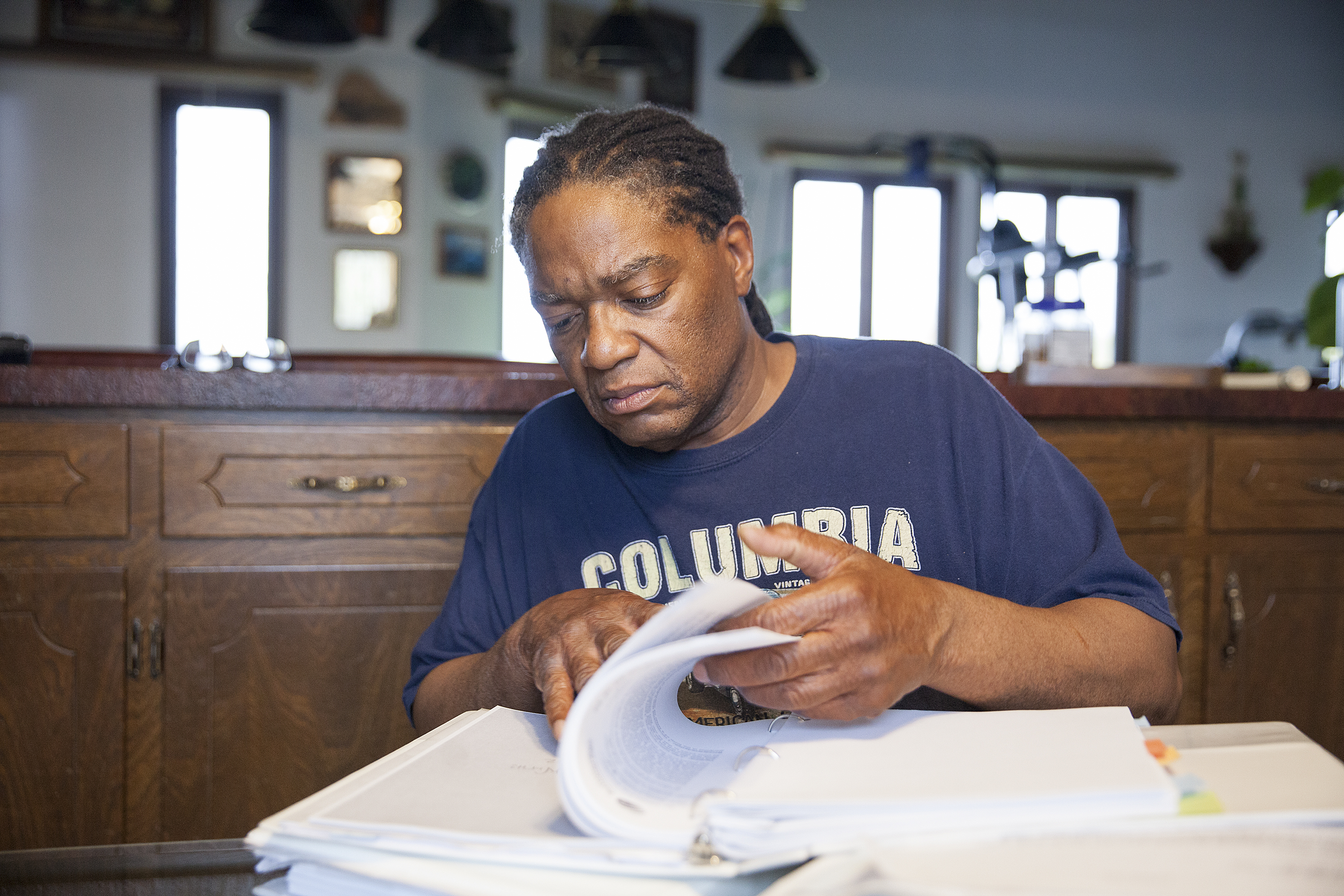 Theodore “Teddy” Burns looks through documents from his discrimination case at his home in Anchorage. Burns’ appeal with the Alaska Ombudsman’s office took eight years to complete. (Photo by Rashah McChesney, KTOO - Juneau)