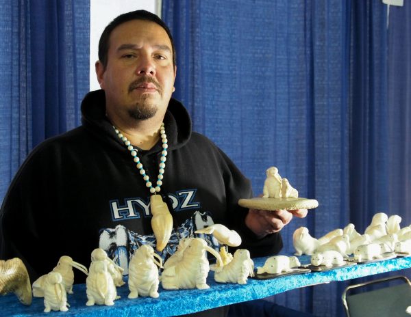 Dennis Pungowiyi shows off one of his favorite carving motifs, a mother walrus with her pup. (Photo: Zachariah Hughes, Alaska Public Media - Fairbanks)