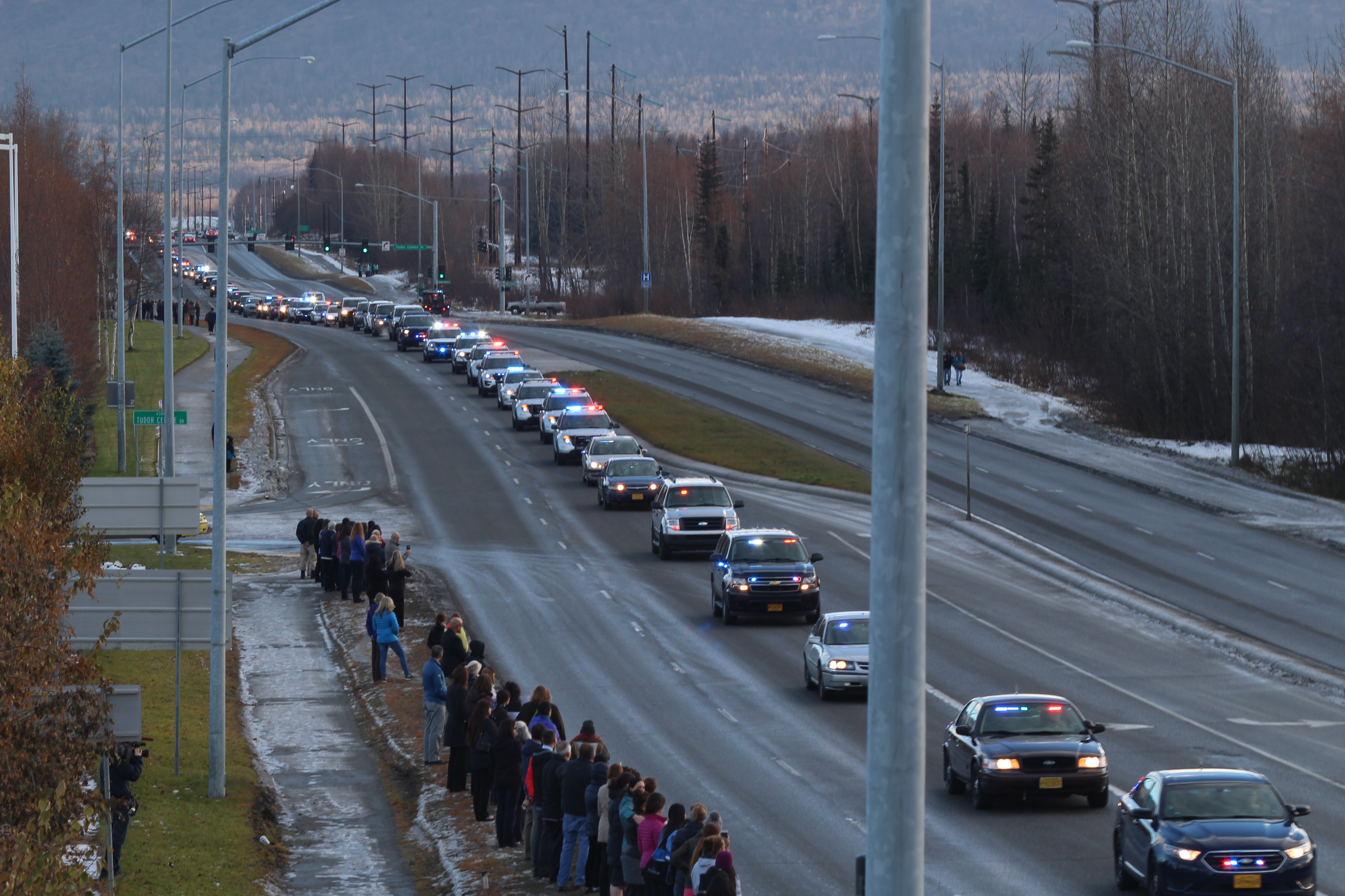 Anchorage citizens watch as a police escort brings FPD Sgt. Allen Brandt’s body to Ted Stevens International Airport for transport to Fairbanks (Photo by Wesley Early, Alaska Public Media – Anchorage)