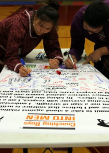 Two student wrestlers sign the poster after completing the ‘Coaching Boys into Men’ program. (Photo by Emily Russell, KCAW - Sitka)