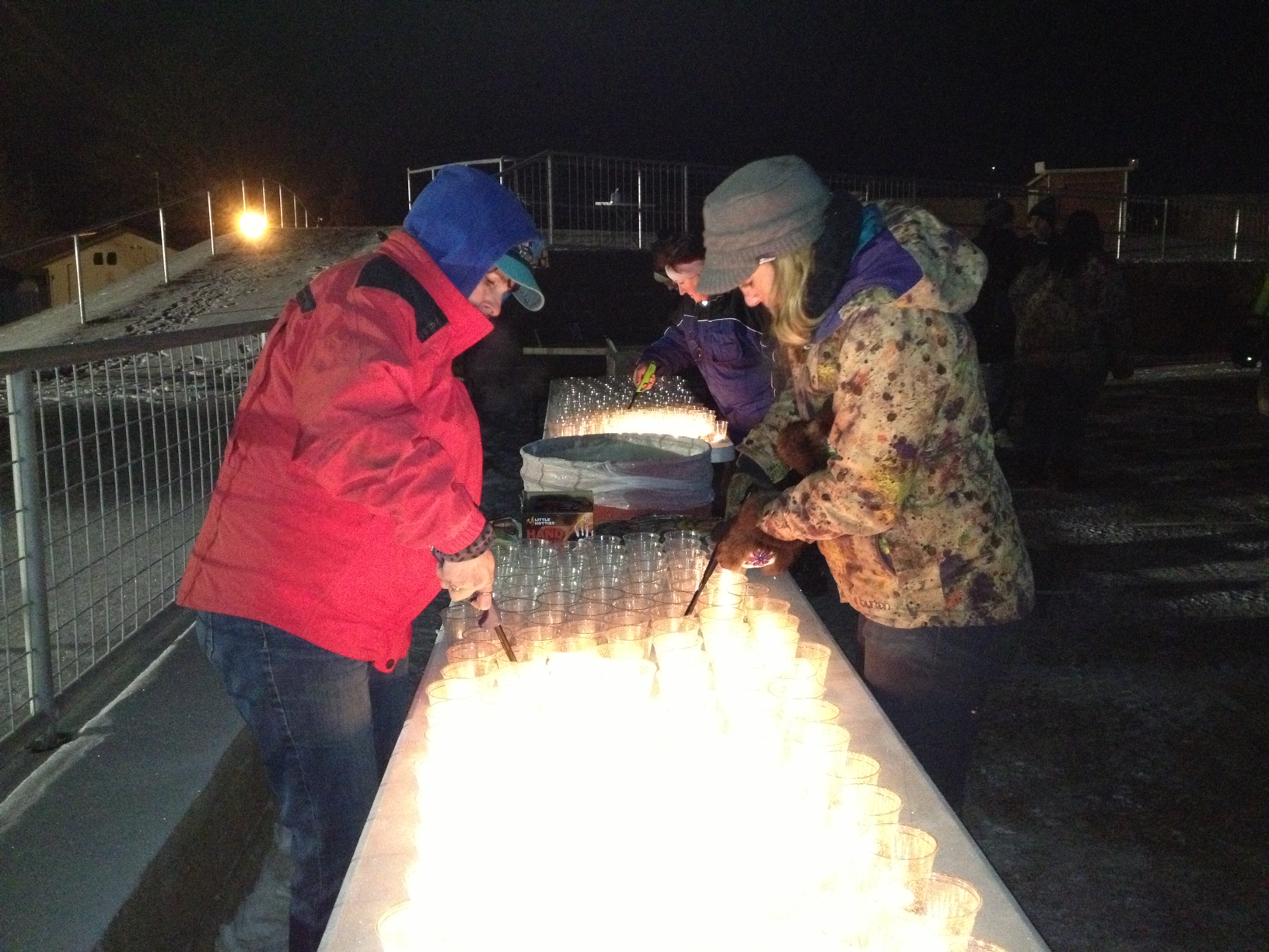 Azlyn Brandenburg and Catherine baher light votive candles before prayer vigil for David Grunwald on Friday. (Photo by Ellen Lockyer, Alaska Public Media - Anchorage)