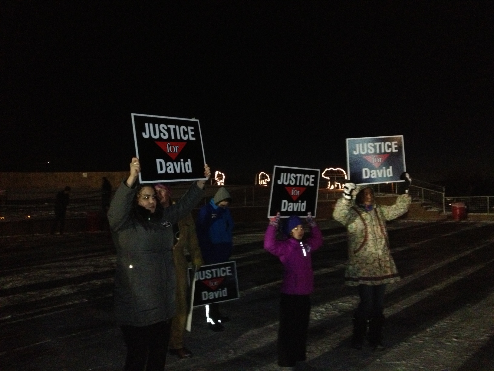 Renee royal and family members hold signs at vigil for David Grunwald on Friday (Photo by Ellen Lockyer, Alaska Public Media- Anchorage)