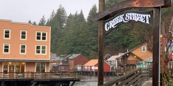 Rain falls in town next to a wooden sign that says "creek Street"