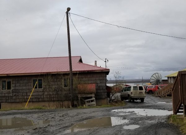 Puddles in front of a log cabin, Mountain Village's office building in 2018 