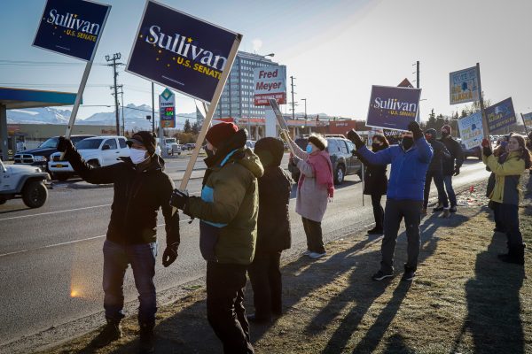 People gathered on the side of a road hold up Dan Sullivan campaign signs.