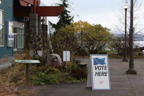 A sign that reads "Vote here" is propped up outside a polling location.
