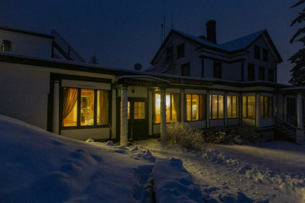 Hundred-year-old hotel with lighted windows in the snow in Haines, Alaska.