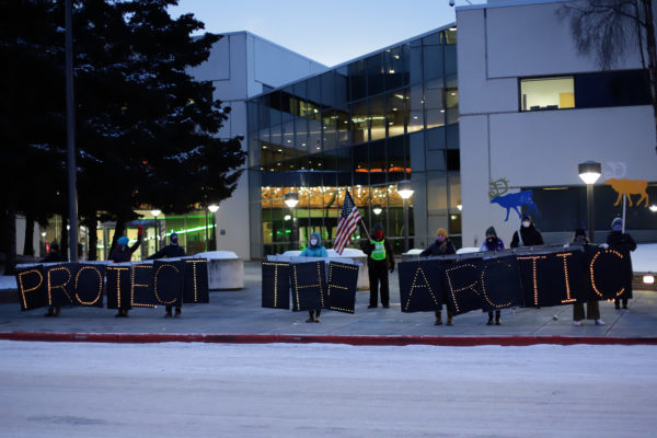 a group of people standing with light-boards that spell out "protect the arctic"