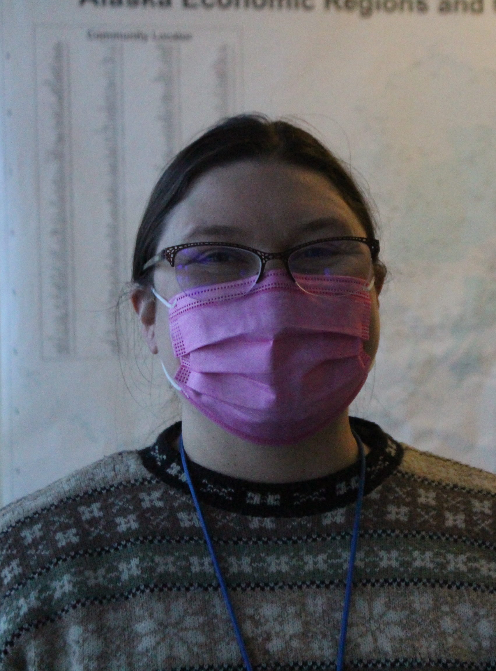 A white woman in a wool sweater and a mask and glasses