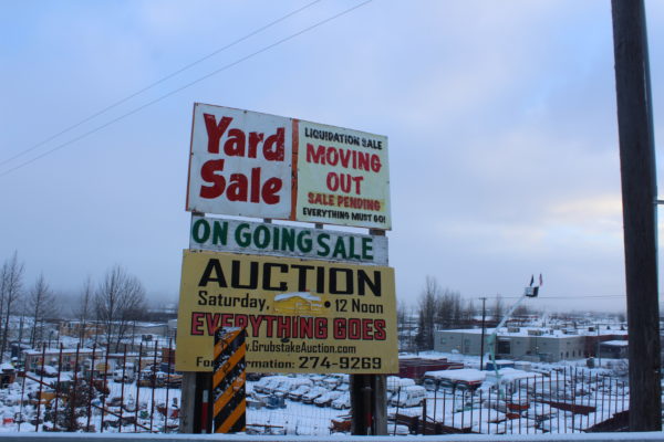 A bunch of machinery covered in snow behind a sign that advertizes and auction
