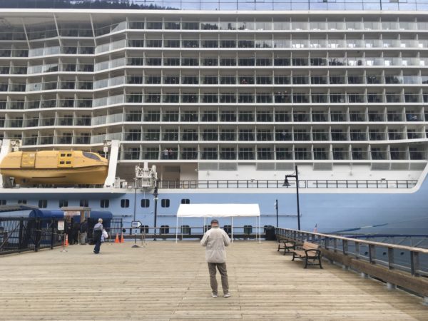 a person stands in front of a giant cruise ship