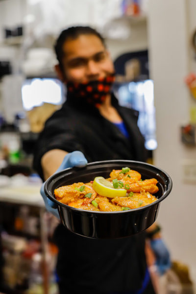 a person holds a bowl of butter garlic shrimp