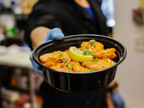 a person holds a bowl of butter garlic shrimp