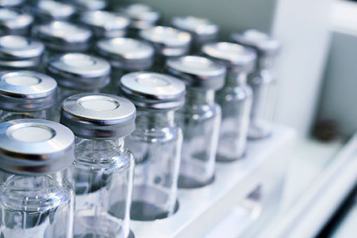 Abput a dozen glass vials on trays