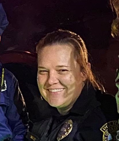 A white woman smiles into the camera wearing a uniform