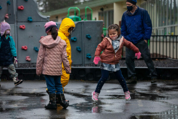 A group of children play in puddles.