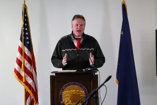 A man behind a podium with flags on either side.