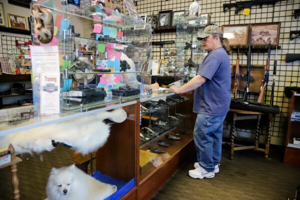 a person purchasing guns and a dog inside a glass counter at a gun store