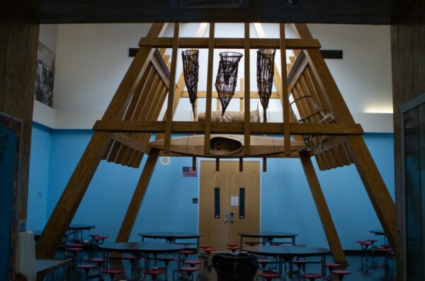 Photo of inside of a school cafeteria with snowshoes hanging above the tables