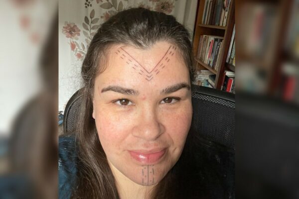 A woman with black hair and a triangle face tatoo on ther forehead