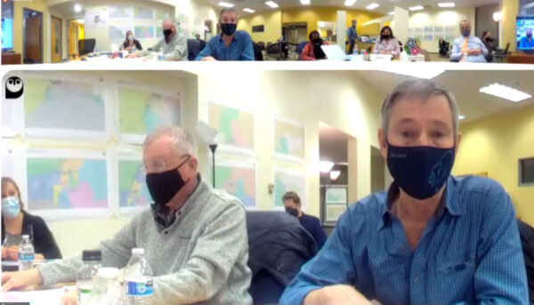 A screen capture of a Zoom meeting. The main screen shows two men wearing masks.