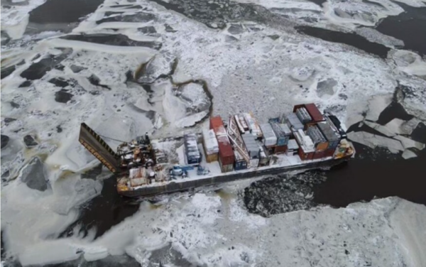 As seen from above, a barge partway frozen in the river