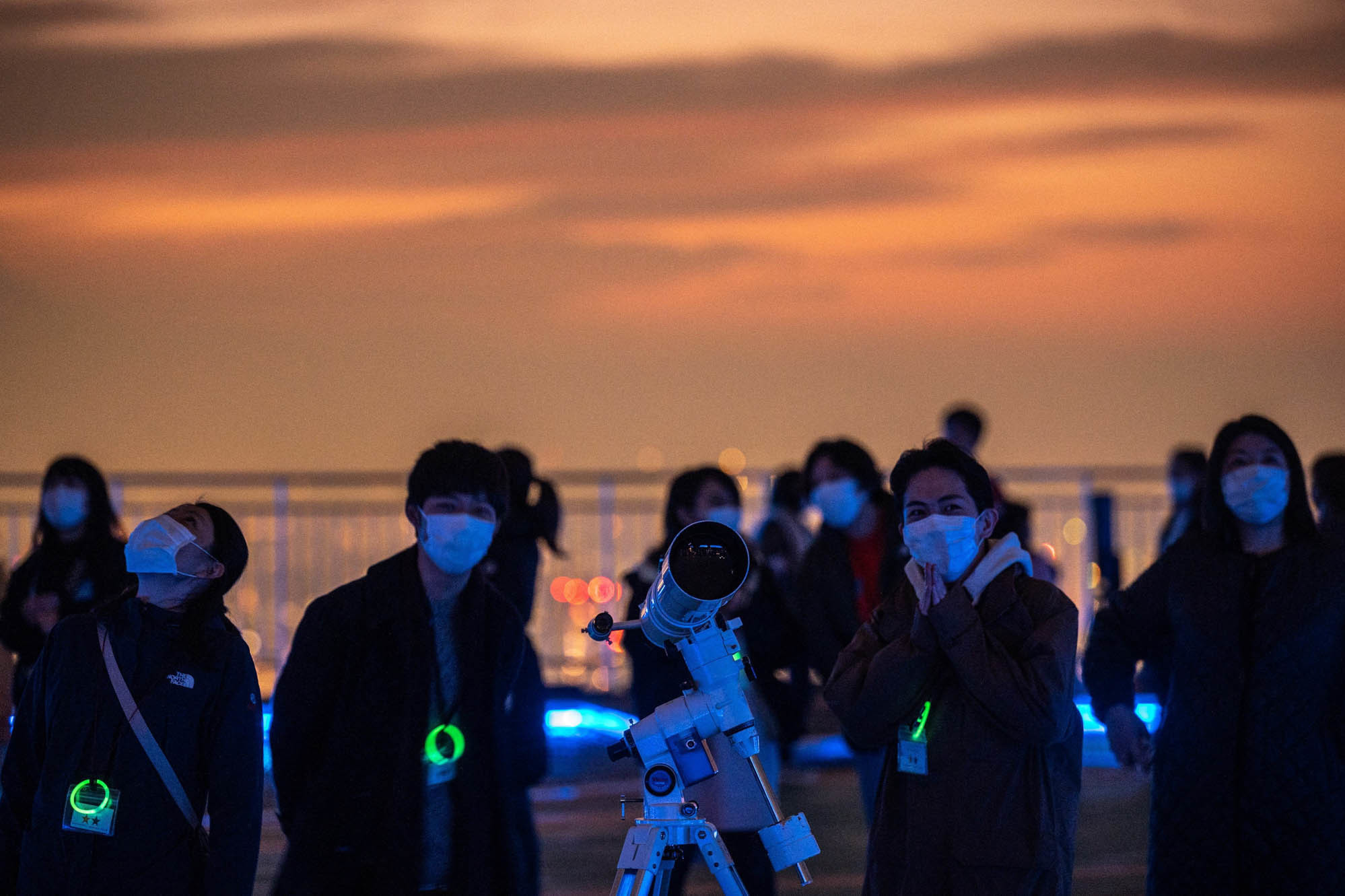 A group of people in masks at dusk outside.