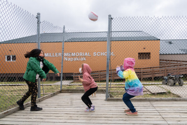 Three students play with a ball outside.