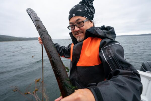 Man holds a piece of kelp standing on a boat