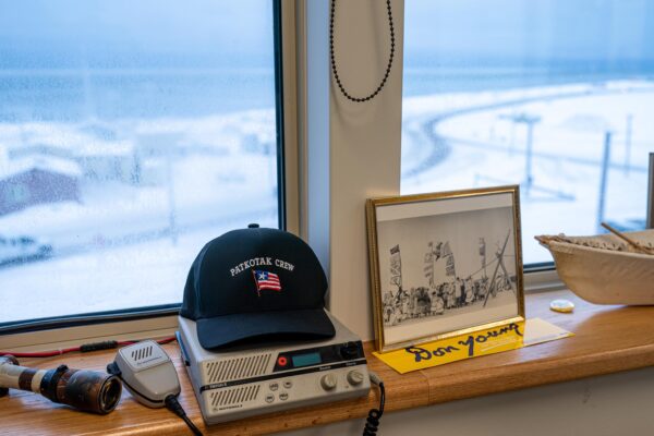 A hat sits on top of a radio near a window.
