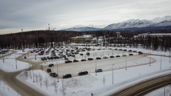 An aerial view of cars snaking through a snowy parking lot.
