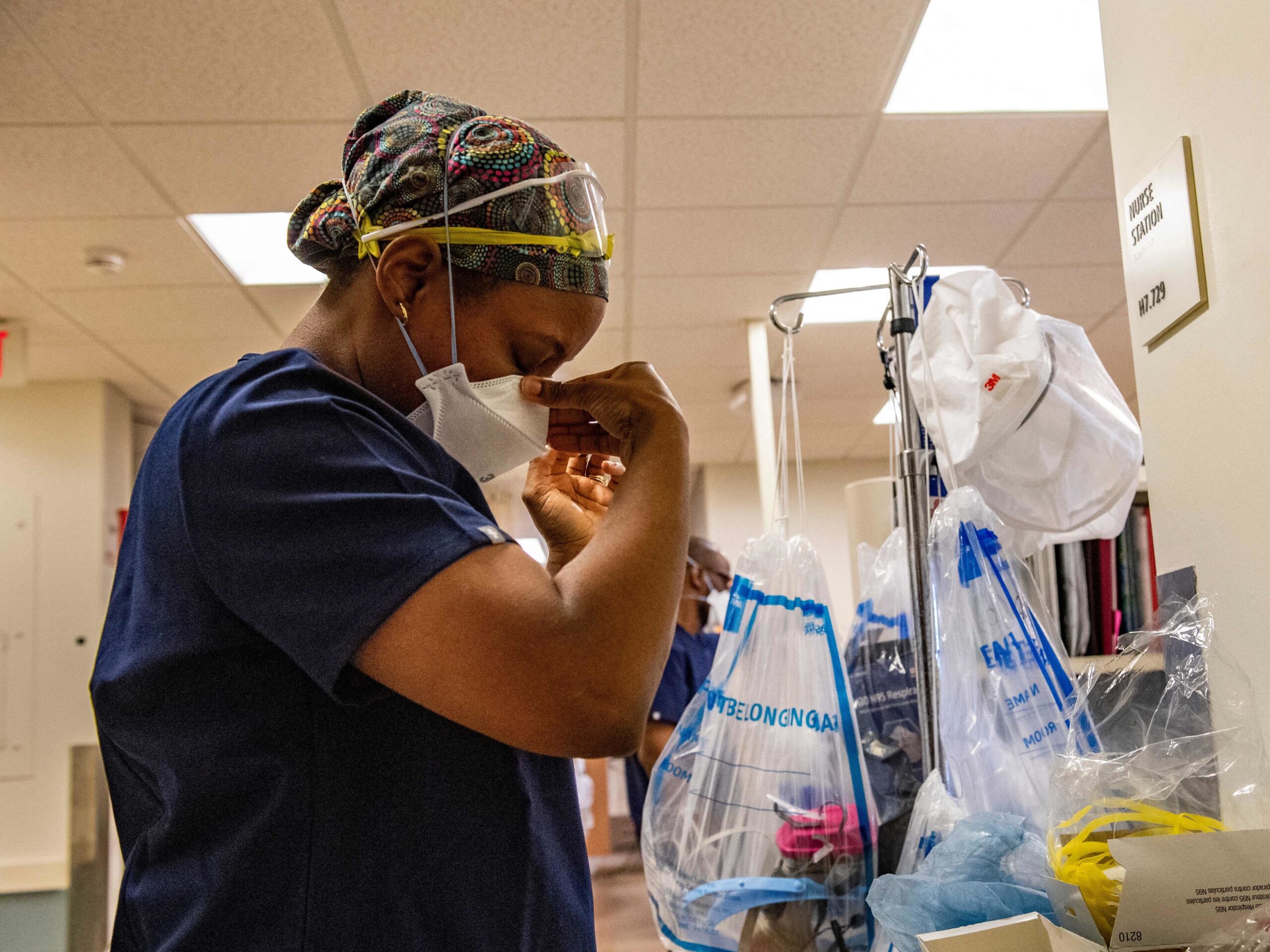 A health care worker fixes her mask.