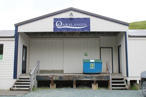 The loading dock of a white building with a sign that says Qawalangin