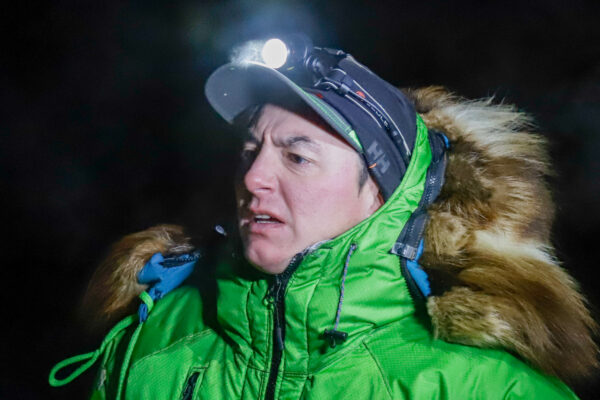 A musher in a green jacket