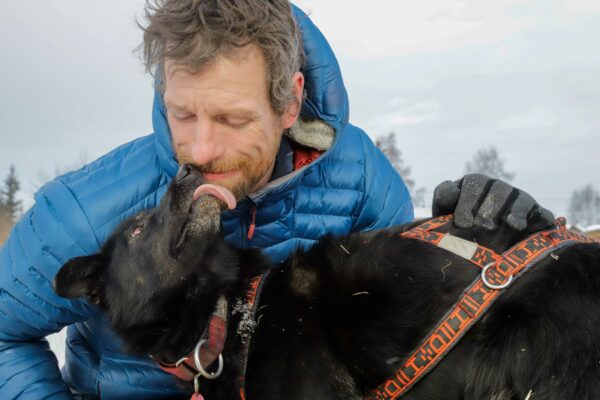 A dog licks the face of a man in a jacket