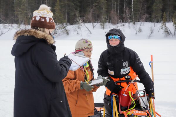 a musher arrives to Nikolai and checks in with race officials