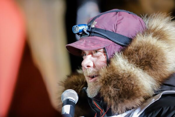a musher speaks into a microphone at the end of a race
