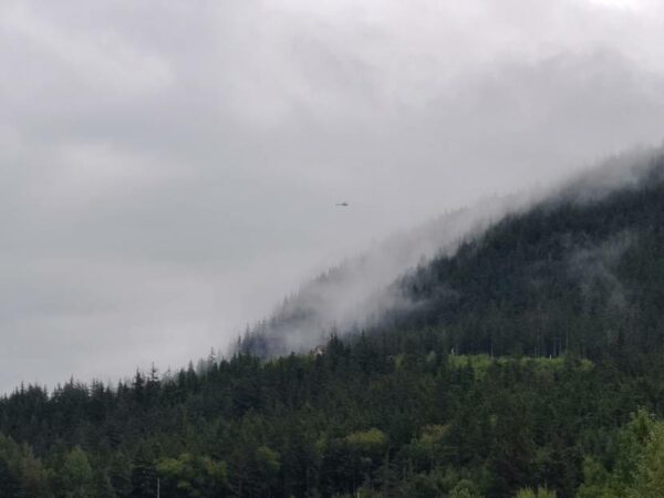 A helicopter over a steep, foggy hillside