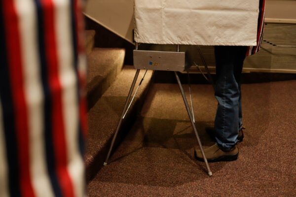 a person stands in a voting stall
