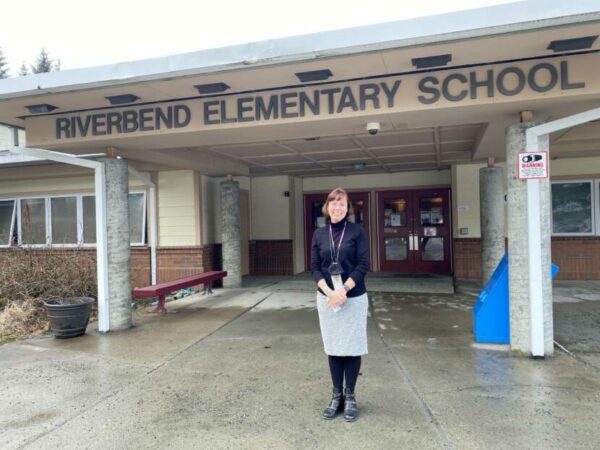 A woman stands in front of a school