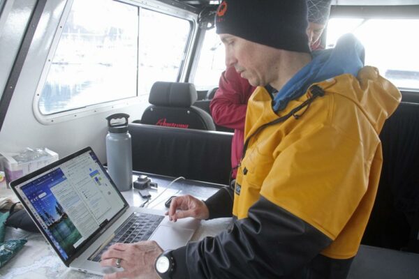 A man on a research vessel studying a laptop screen